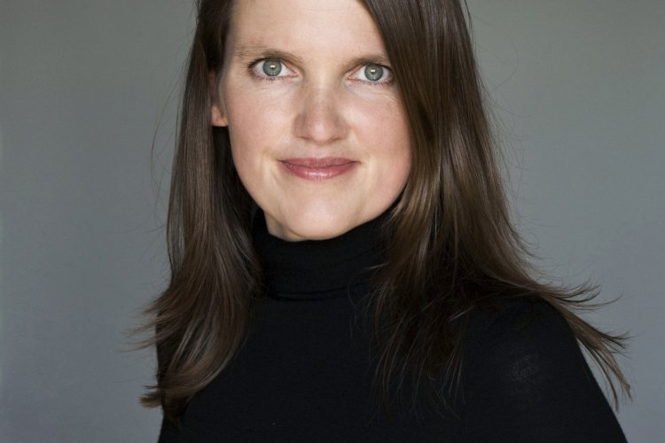 Katrin Hörnlein in schwarzem Rollkragenpullover mit offenem Haar vor grauem Studiohintergrund