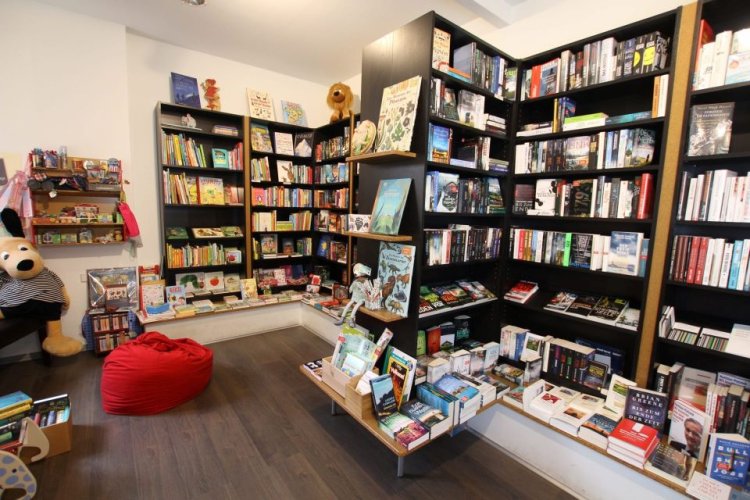 Volle Bücherregale im Buchladen mit Sitzmöglichkeiten und Kissen