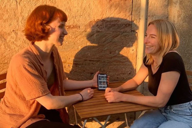 Jana Brammer und Valerie Hentschel sitzen im Sonnenuntergang im Freien und sprechen